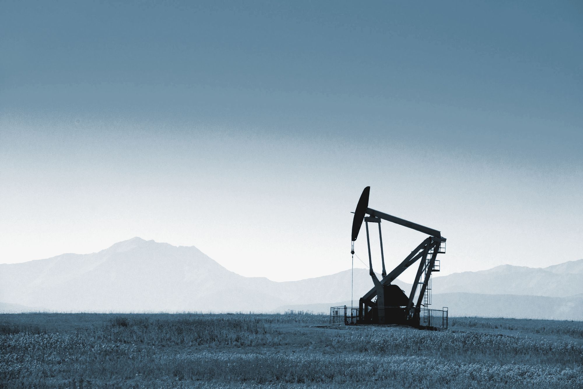 A pumpjack on open range under a wide sky